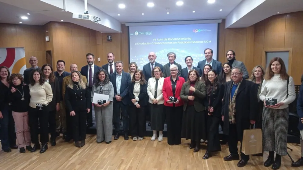 Un grupo de personas reunidas posando para la foto en forma de semicírculo con el obsequio en la mano